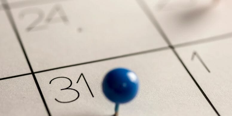 desk calendar with a blue push pin on day 31